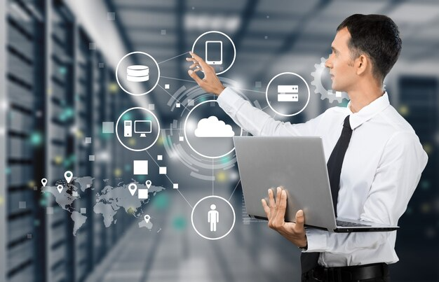 A professional using a laptop, interacting with digital icons and cloud technology in a data center environment.